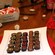 A table set with a plate of chocolates and 2 stemmed glasses filled with wine